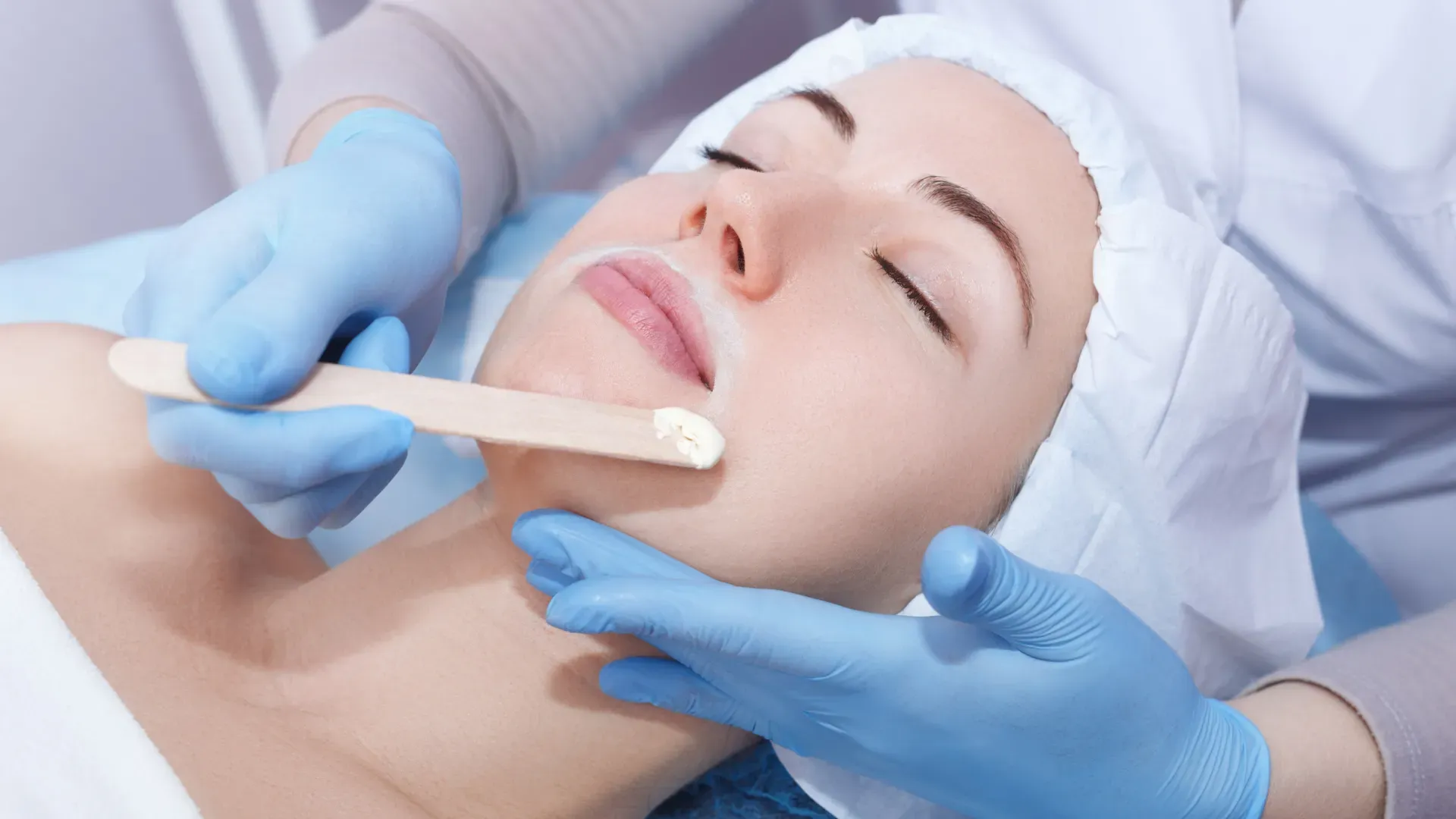 Technician applying wax during a facial waxing treatment