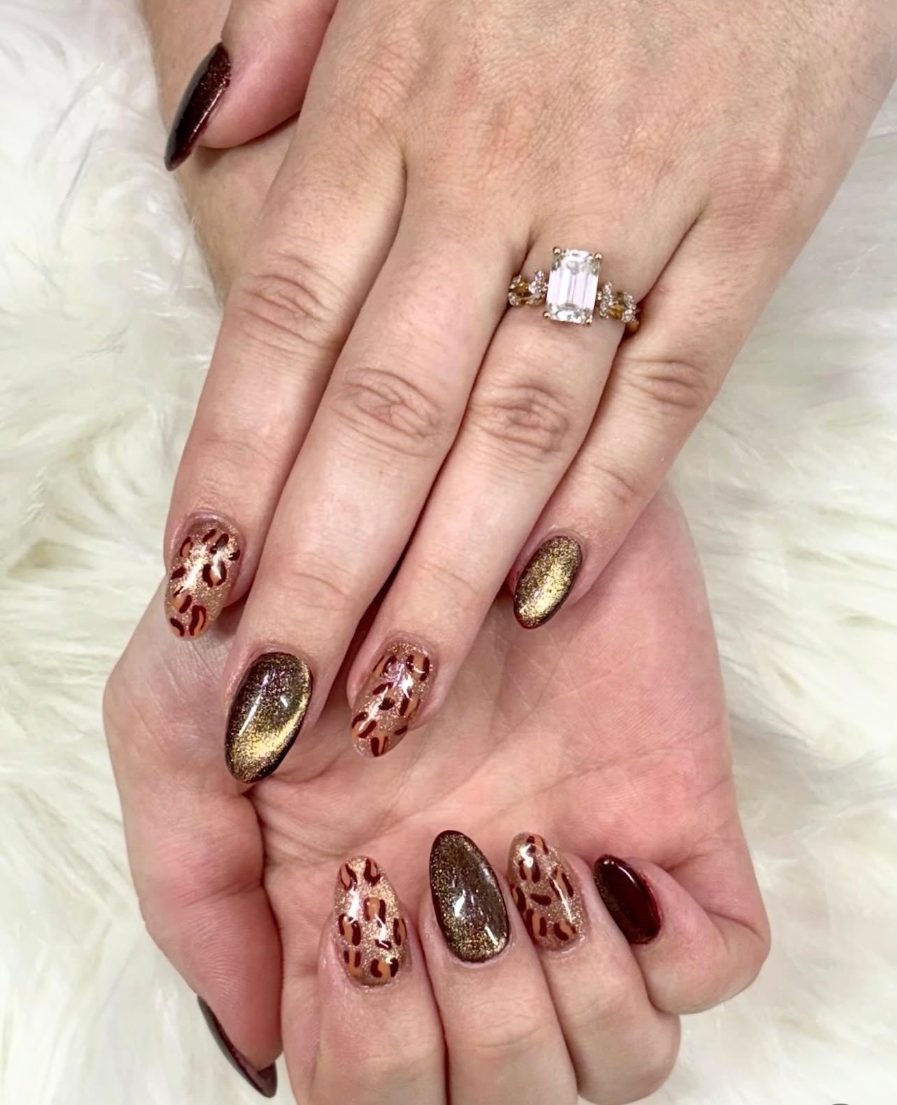 Gold cat eye nails paired with burgundy polish and patterned accent nails