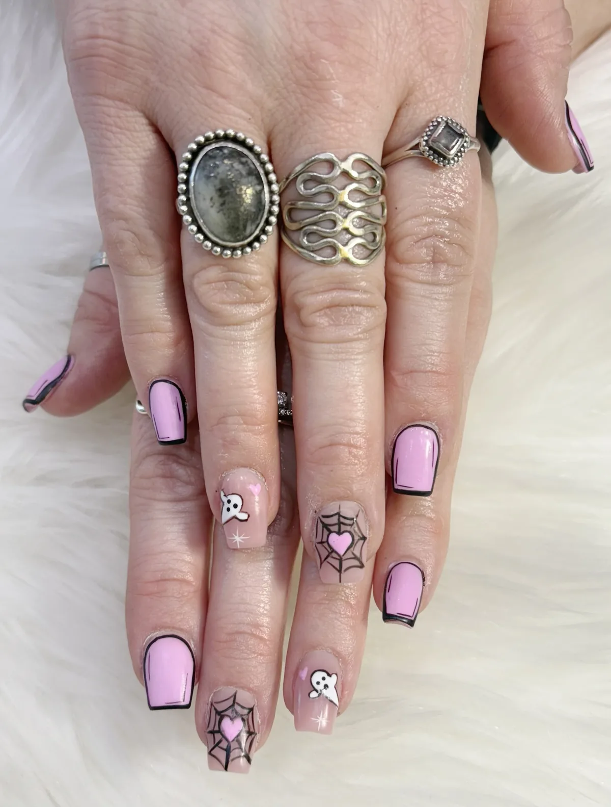 Pink square nails with black outlines, white ghosts and heart-shaped spiderweb accents