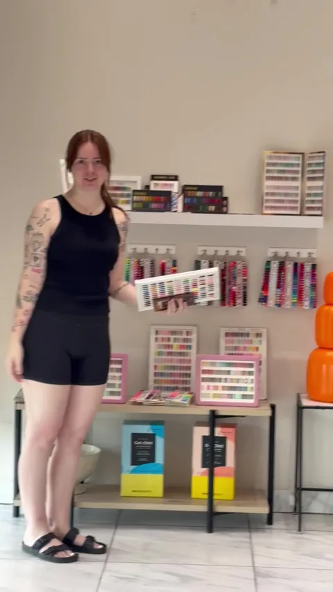 A person holding a nail-color sample display inside Apple Nailed It Spa