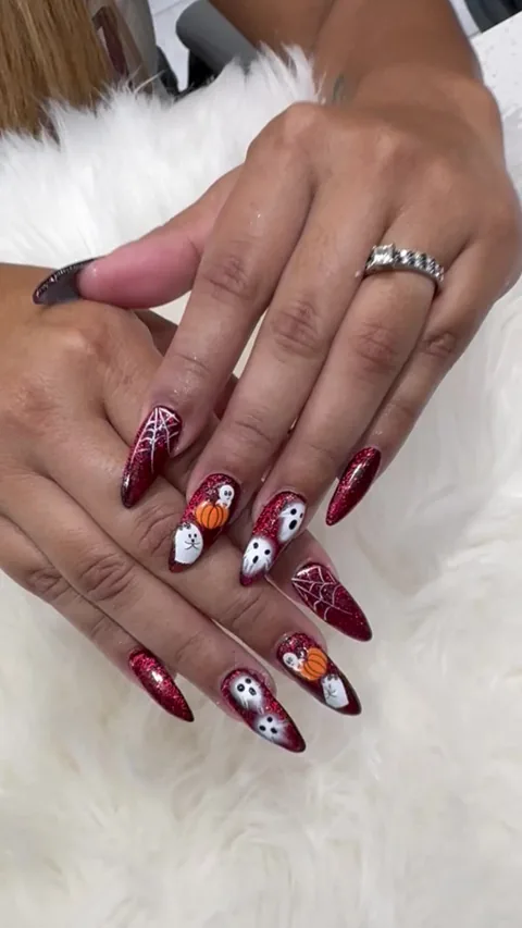 Red glitter pointed nails with white ghosts, pumpkins and spiderwebs