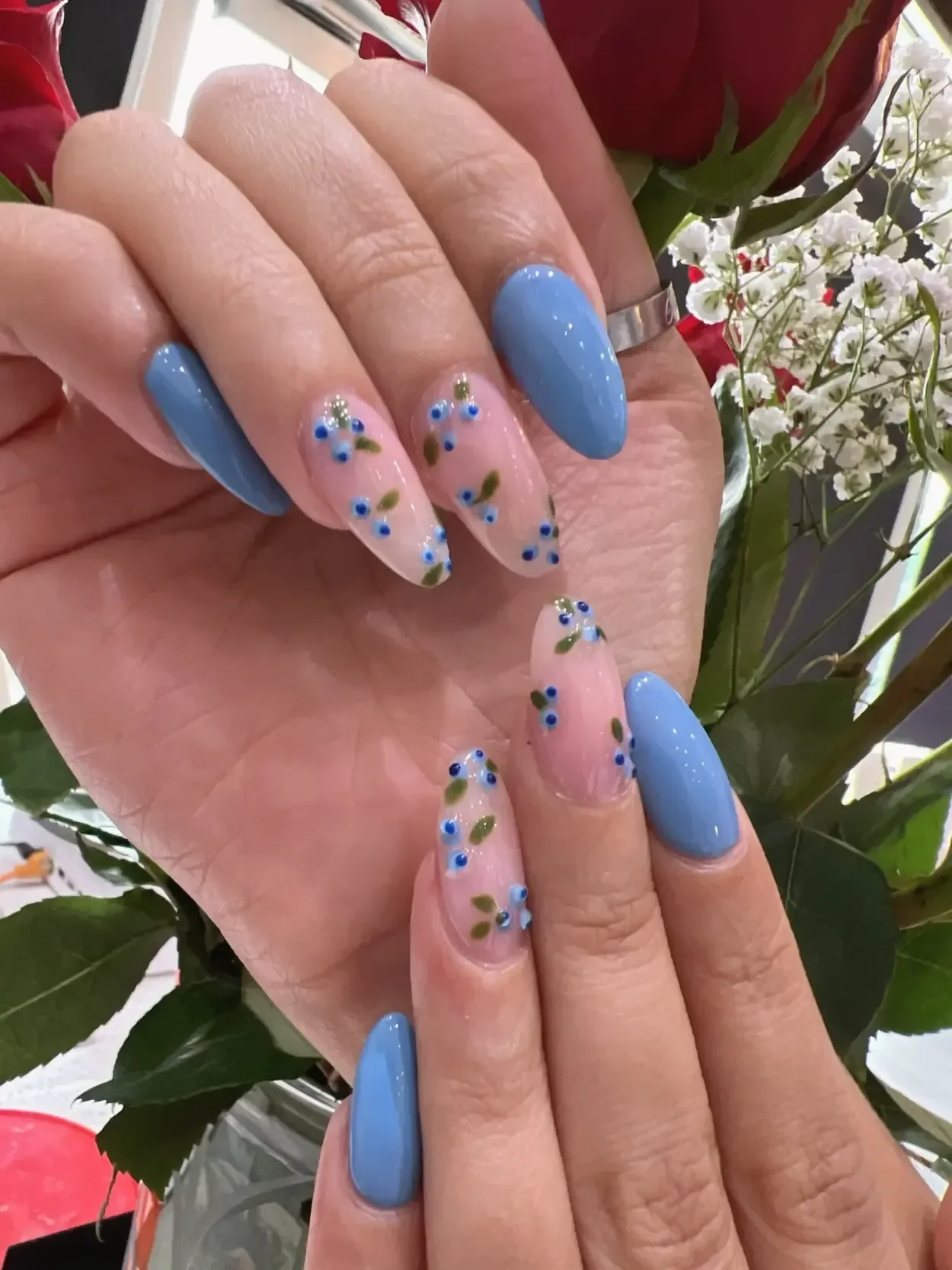 Blue almond-shaped nails with small floral accents